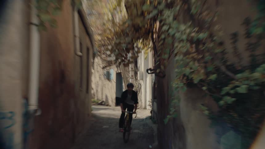 A man is recklessly riding his bike between buildings