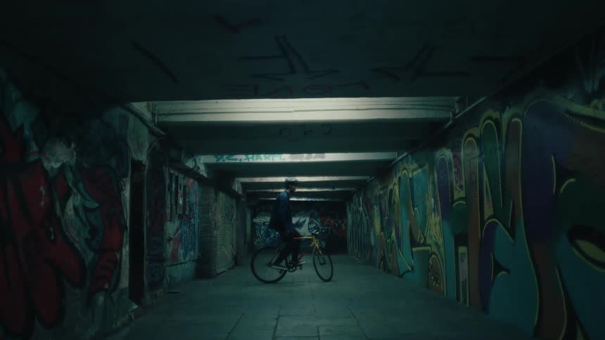 Man sitting on a bicycle in the spray painted graffiti filled hallway in a subway station