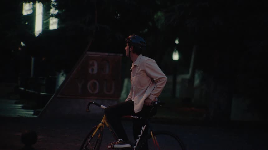 A man on a bike is stopped on the side of the road waiting for traffic to clear