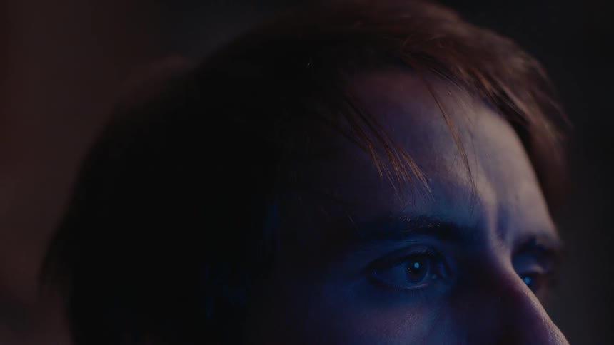 Extreme close up of a young man using a electronic device in a room at night