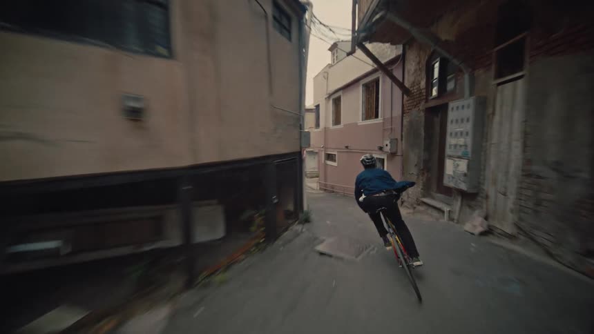 A young man cycling through alleys in a suburban city at sunset