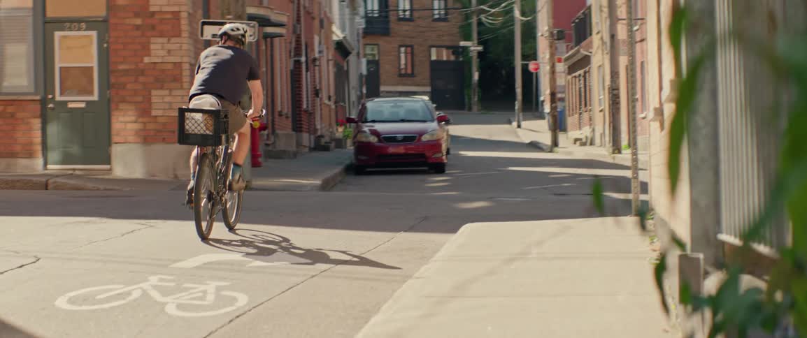Man rides his bicycle on a neighborhood alley between buildings