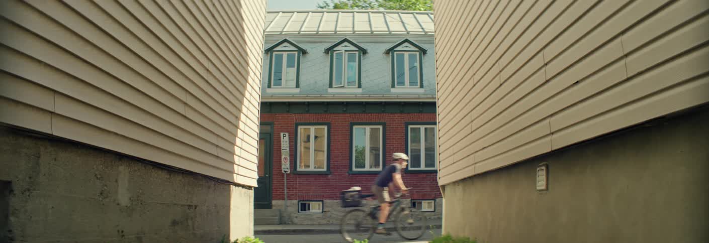 A man wearing a helmet is riding a bicycle through residential street