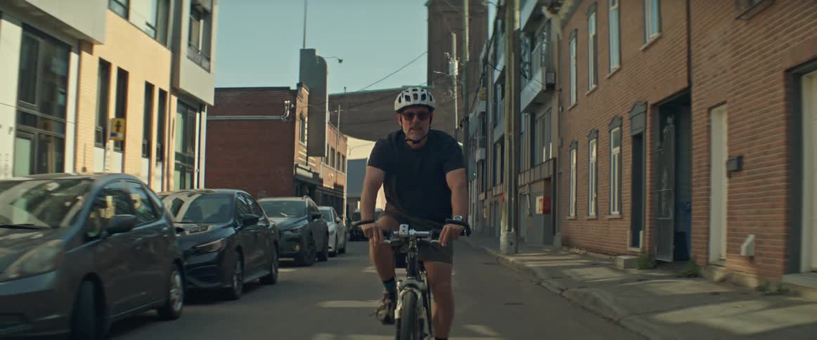 Cyclist rides through a narrow street between residential buildings