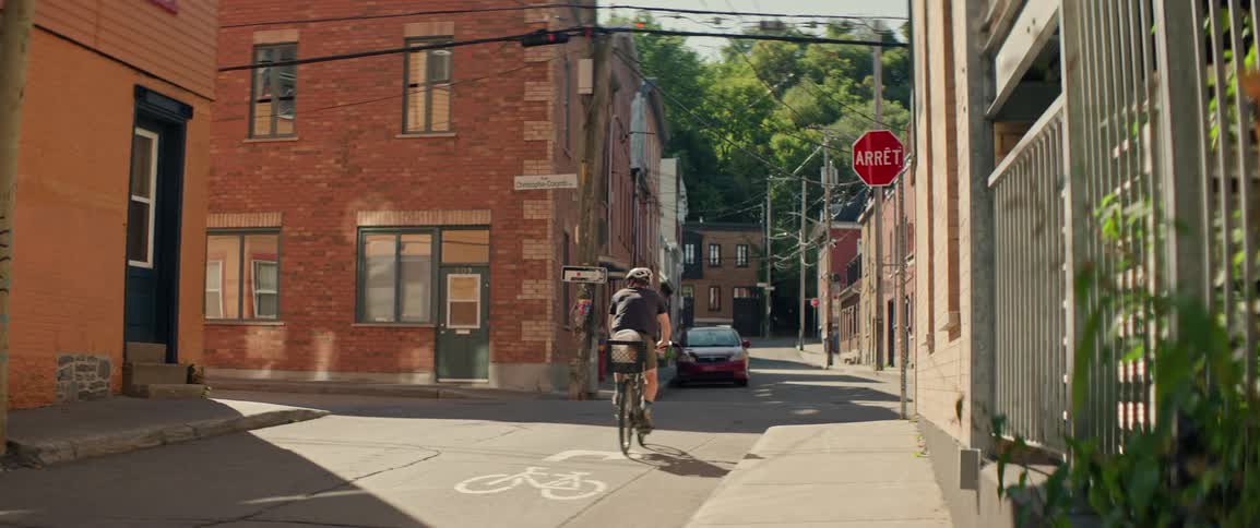 Man rides his bicycle on a neighborhood alley between buildings