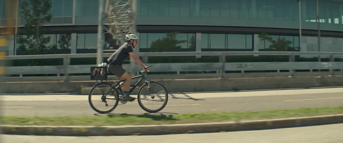 Male cyclist pedals his bicycle along an urban lane on a summer day