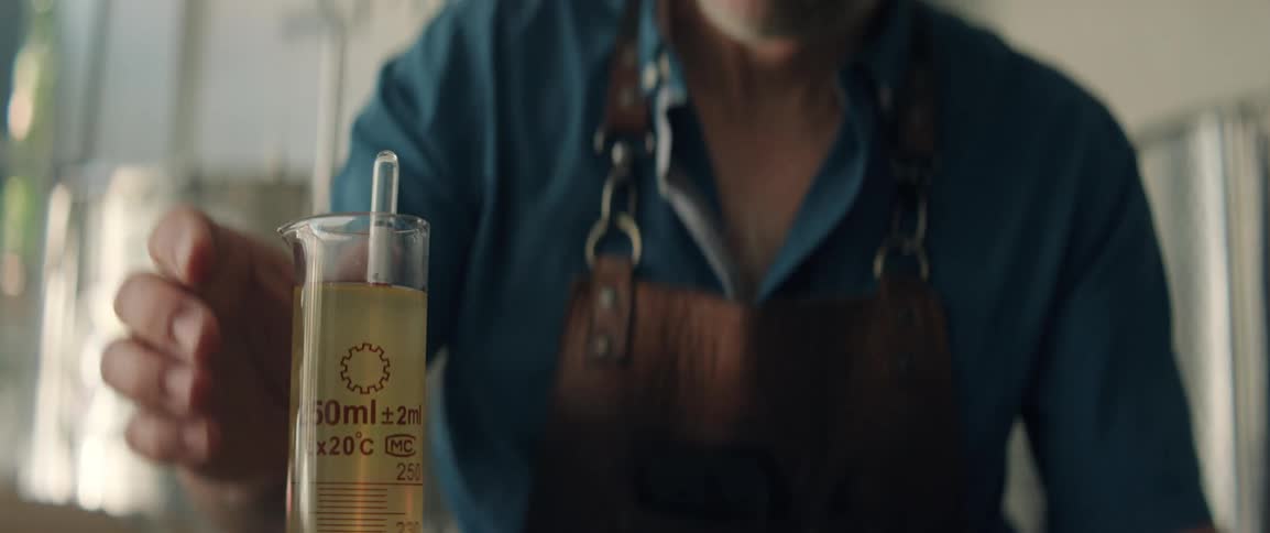 A worker in a distillery puts liquid in a beaker