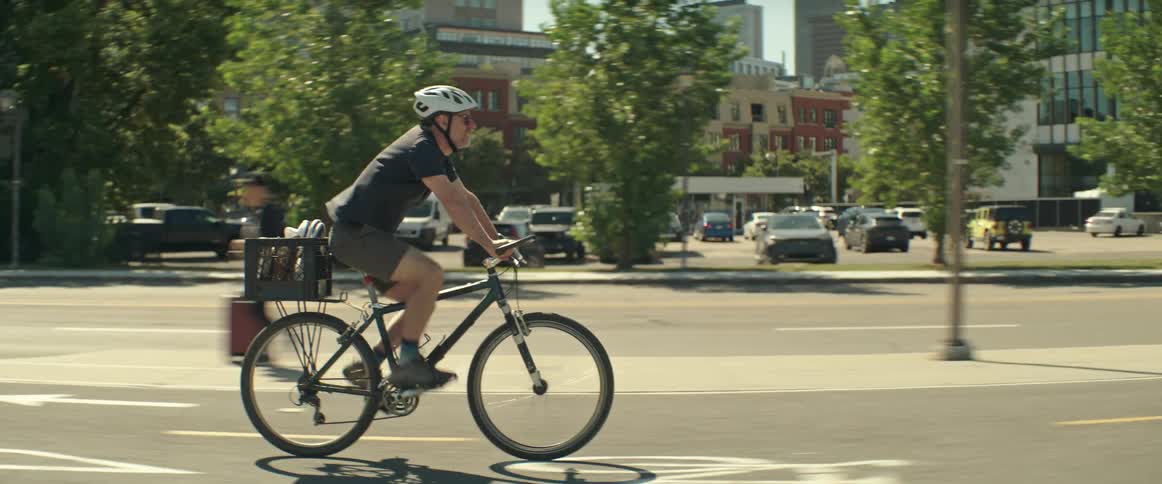 A man is riding his bike through the city as other people move around him