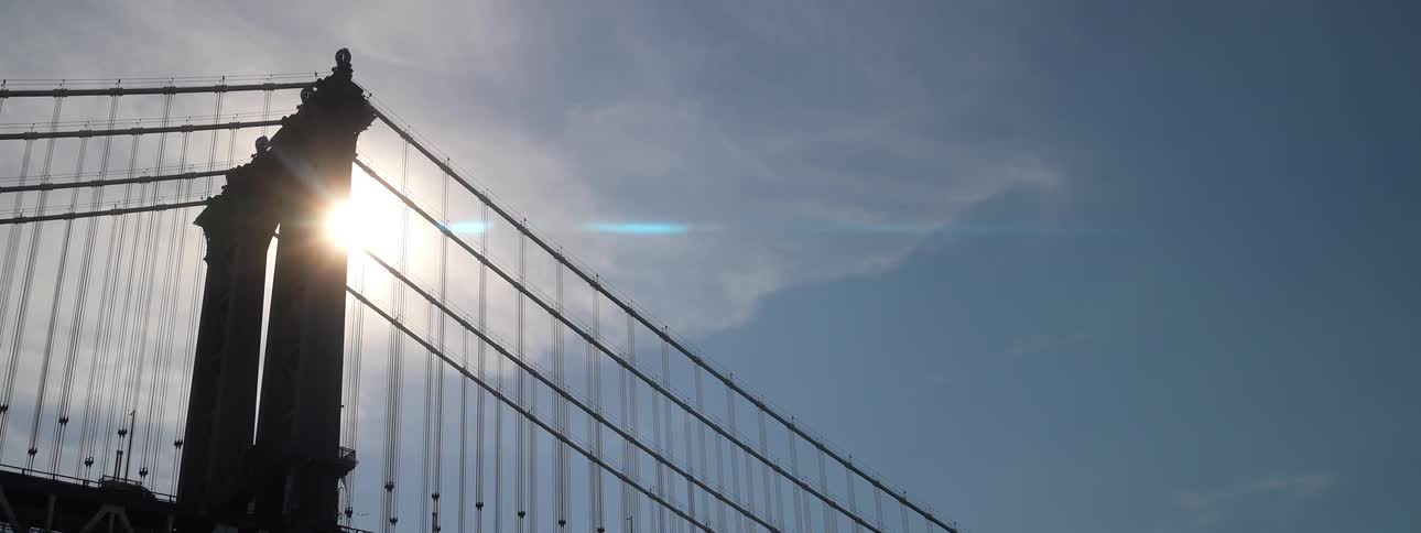 Sun shines past a cable bridge on a cloudy day
