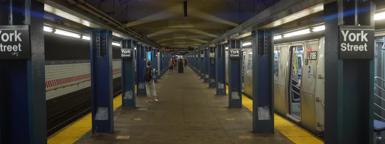 Train stopped in the station as people stand waiting for their train
