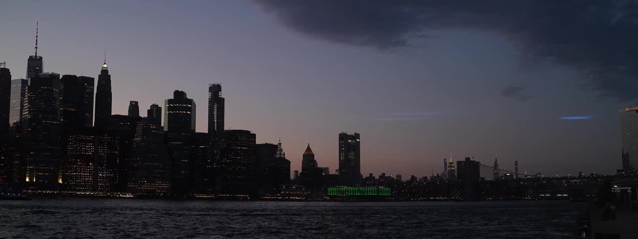 The tall buildings of a city skyline are illuminated at nighttime