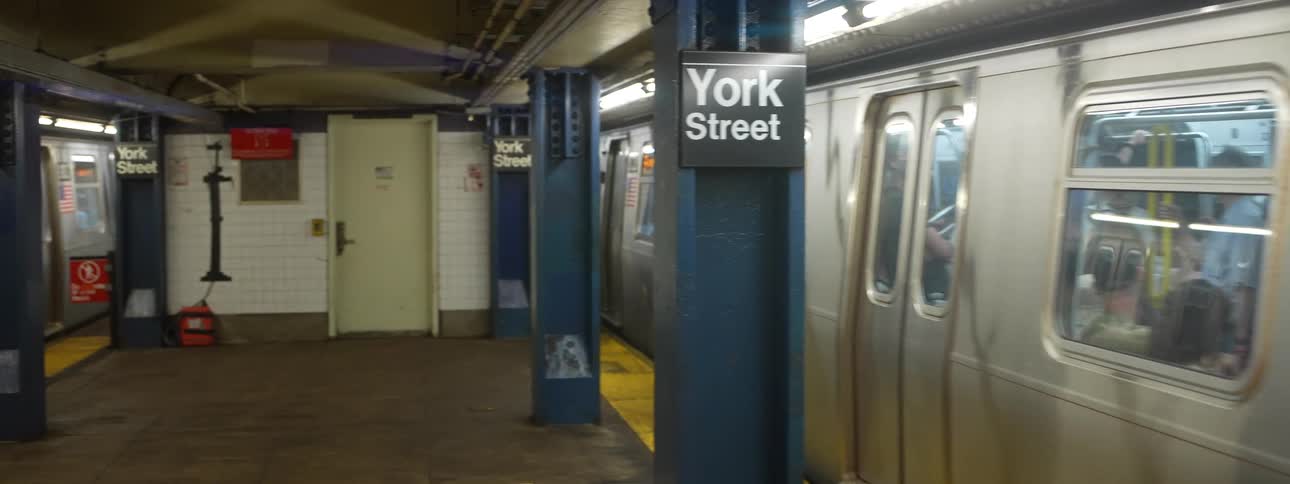 Metal train passes through york street station with closed doors