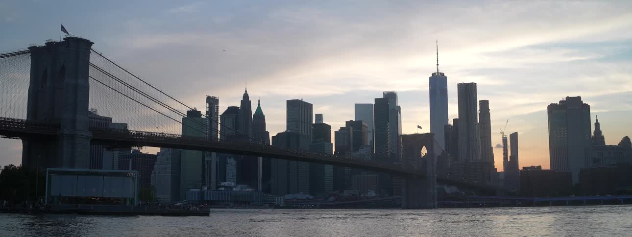 Bridge and skyscrapers at dusk form the citys silhouette by the river