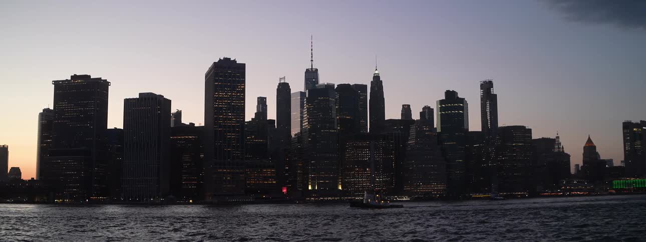 City skyline lit at dusk seen from across the river