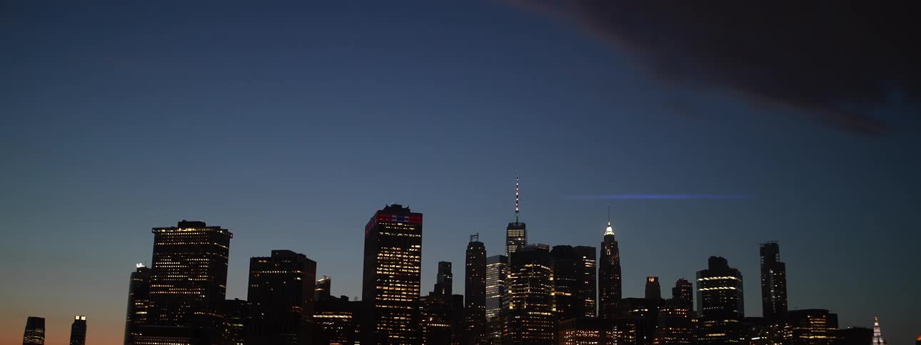 Several tall buildings in a city skyline are illuminated at night