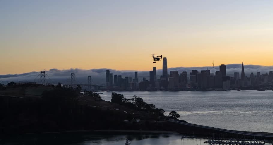 A drone hovering above a waterway in a city at sunset