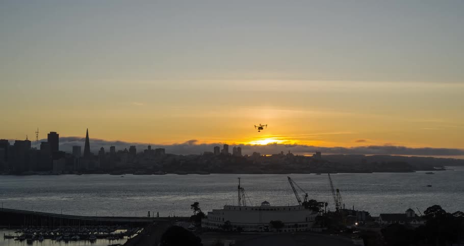 A drone is hovering over boats near a city