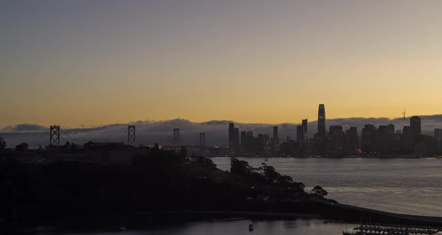 A city skyline silhouetted against the sunset sky