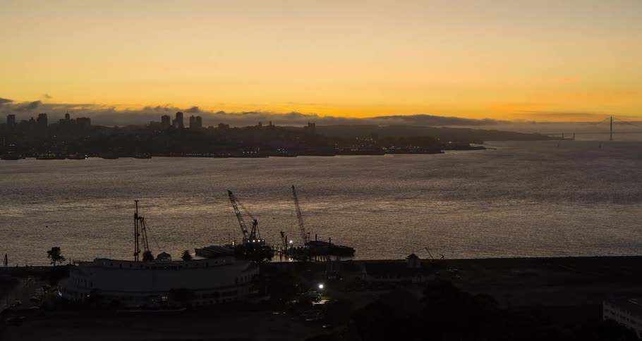 Cranes on the coast with city buildings across the river