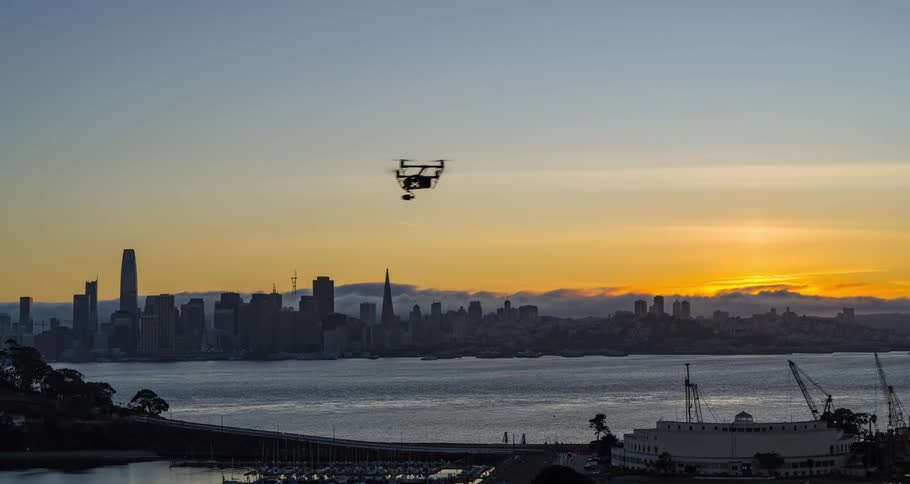 Drone flies over the bay at sunrise with the sun rising behind the city