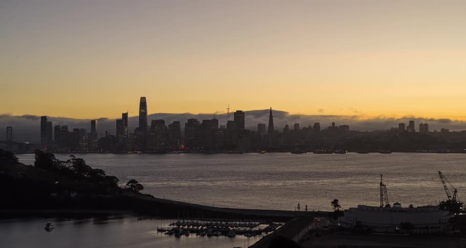 The silhouette of a city with tall buildings on a clear morning with a sea in front