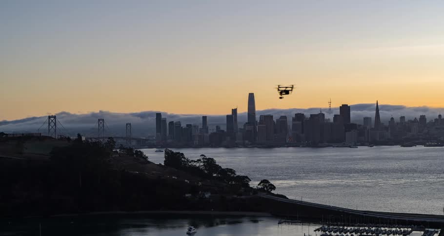 Drone flies over the bay at sunset with the city in the background