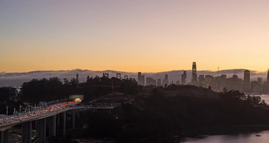 Traffic on the road and bridge with towers and skyscrapers on the city skyline and buildings along the coast