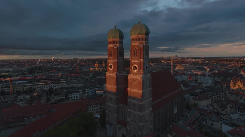 Aerial of twin clock towers in a metropolitan city skyline at sunset