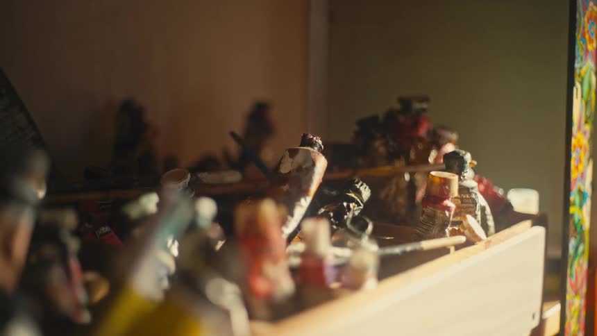Several tubes of used paint in a white drawer that is on a shelf