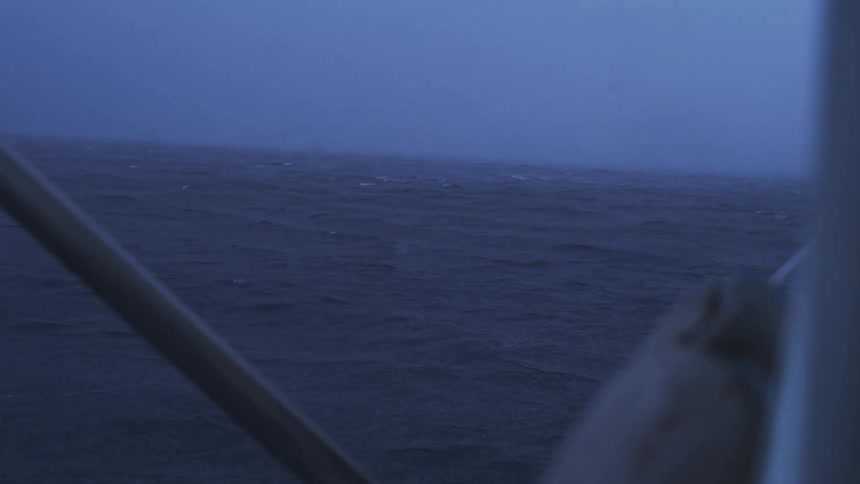 Rough sea seen from a boat deck under blue fog