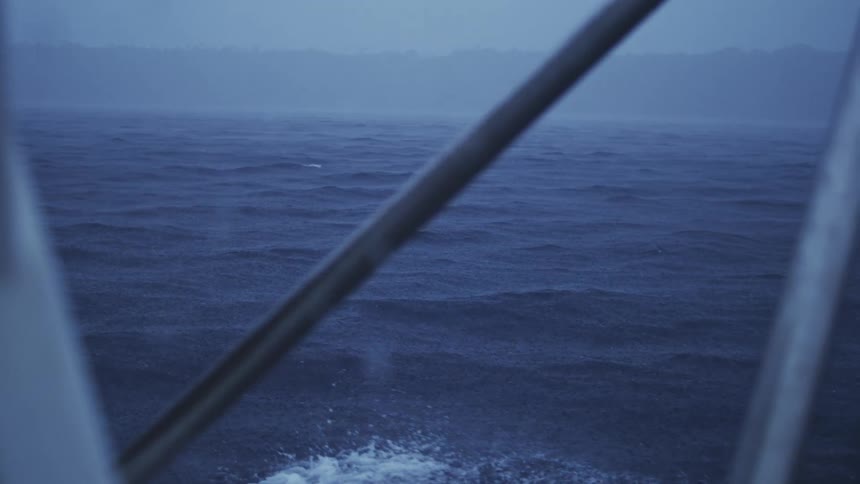 Calm misty sea seen through the rails of a boat