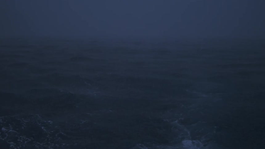 Water ripples and waves as rain falls on a dark hazy evening