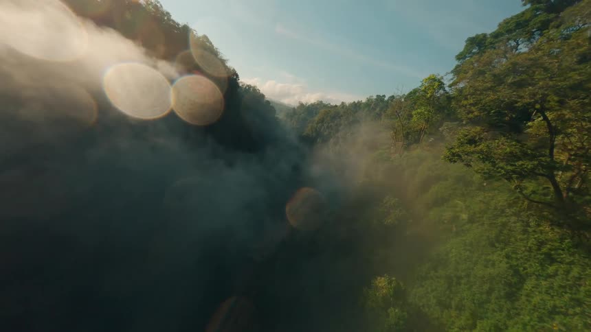 An aerial view of a valley nestled in a mountain of green trees with a mist hanging over the landscape