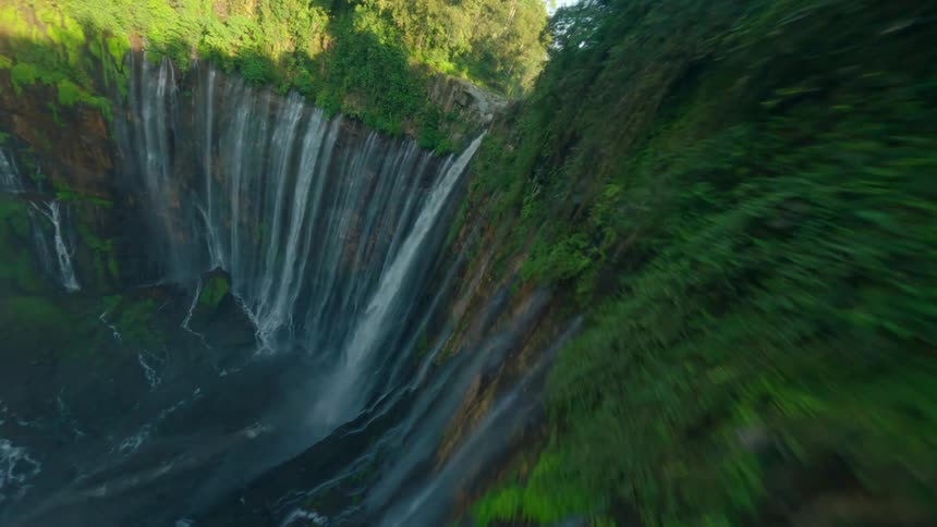 Tall waterfall forms a veil of water over mosscovered rocks