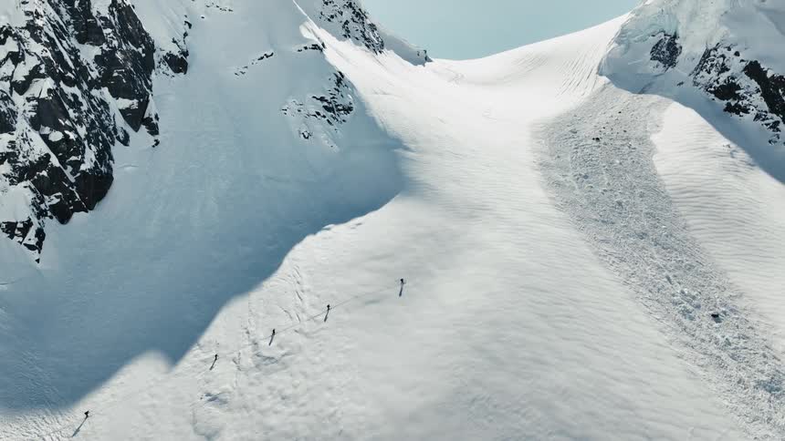 Group of people walking across a snow covered mountain slope