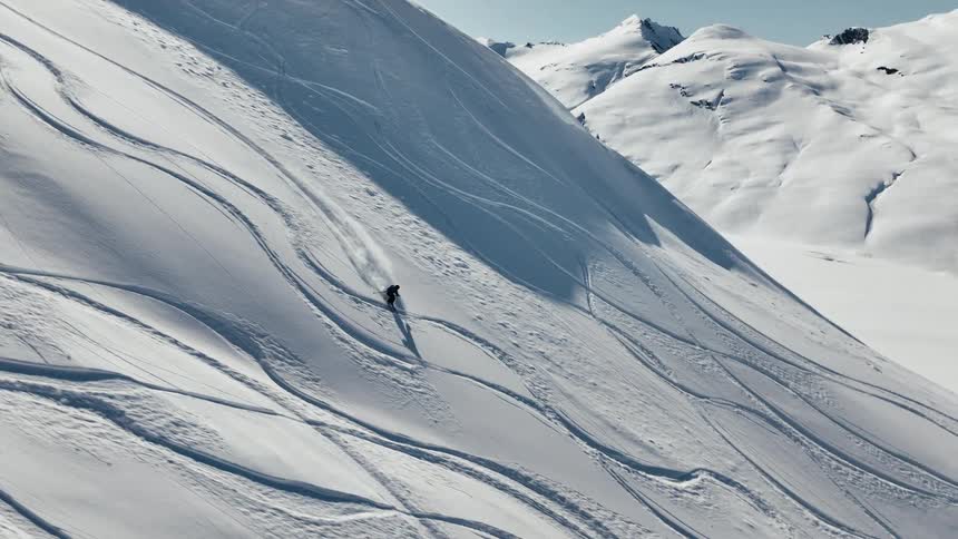 A person is skiing down a mountain that has tracks from other skis