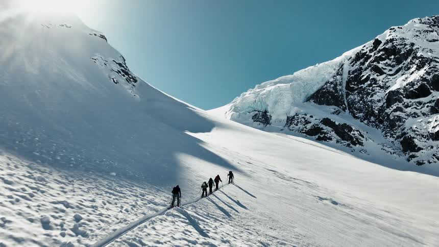 Group of mountaineers walk across a snow covered mountain slope