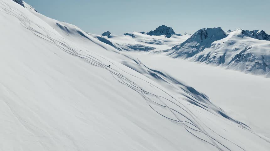 A lone person skis down a snow covered mountain slope