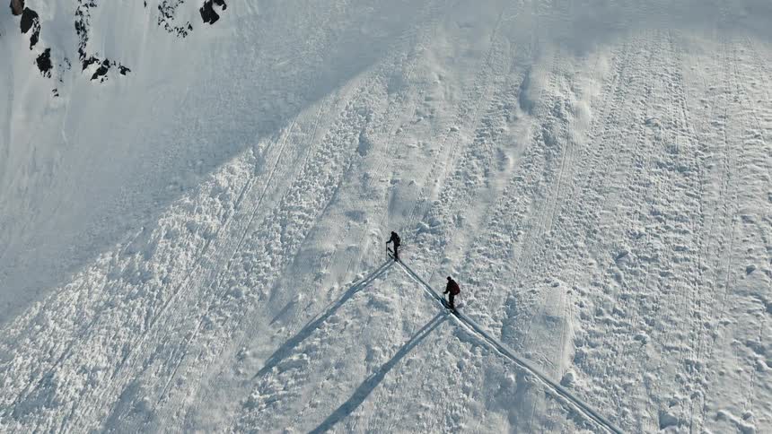 Two skiers make their way up a vast snow covered mountain