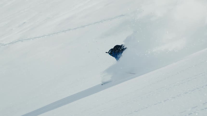 Skier slides down a mountain slope as snow flies