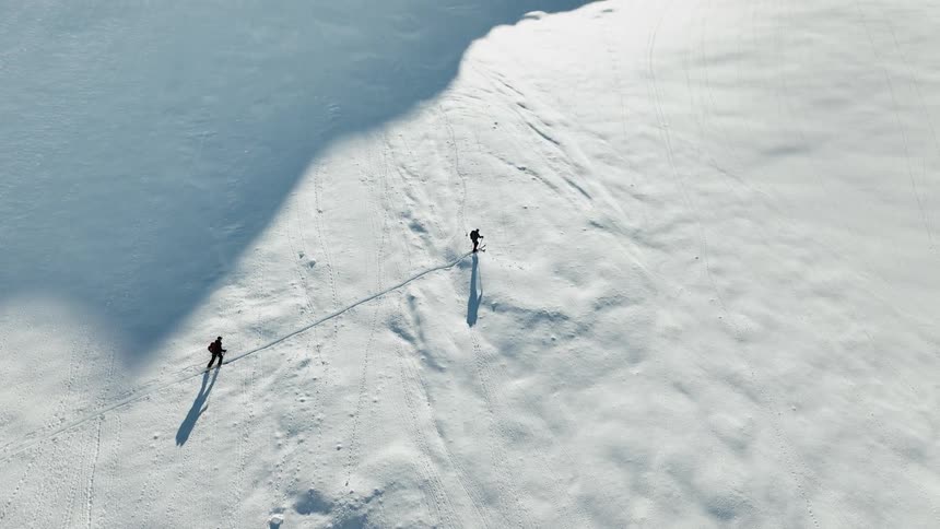 People hold a rope as they walk across a snow covered mountain slope