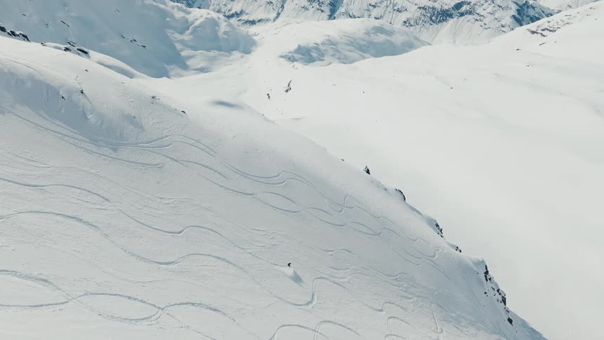 Two people are skiing down a steep snow covered mountain
