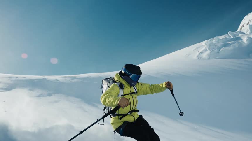 A person skis down a snow covered mountain slope on a bright sunny day