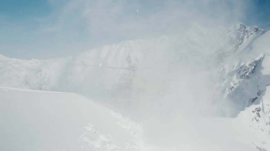 Yellow helicopter landing on a snowcovered mountain