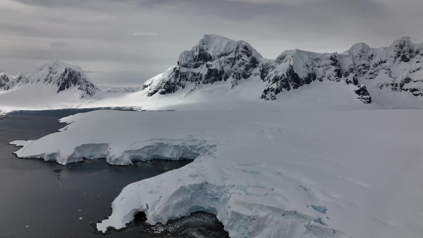Snow covered mountains along the arctic coast under a cloudy sky