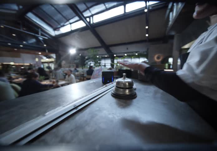 Female chef walks to the counter and taps the bell during the daytime