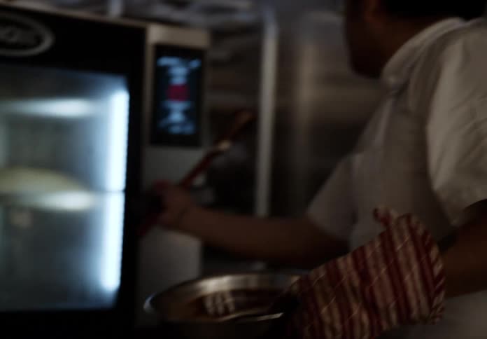 A hispanic man mixes chocolate cake batter before placing it in a refrigerator