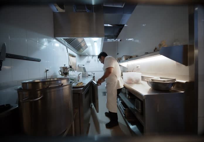 Man plates a slice of cake in a commercial kitchen