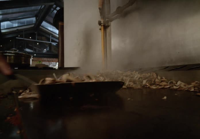 Sliced mushrooms being sauted on a hot griddle