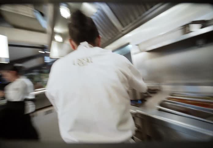 The chef walks into the kitchen of the restaurant and stirs a pot